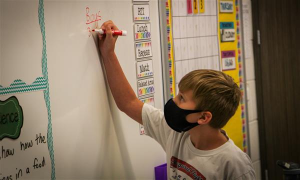student writes on whiteboard